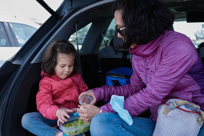 Mom and daughter having snacks in the back of an suv