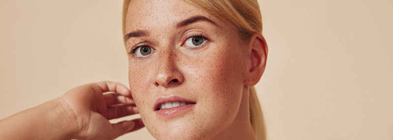 Close-up of young woman against pink background