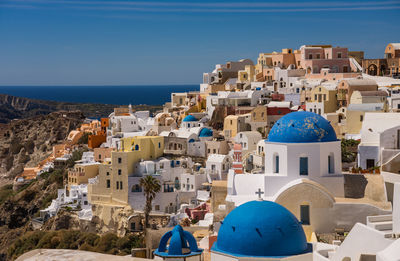 Buildings by sea against blue sky