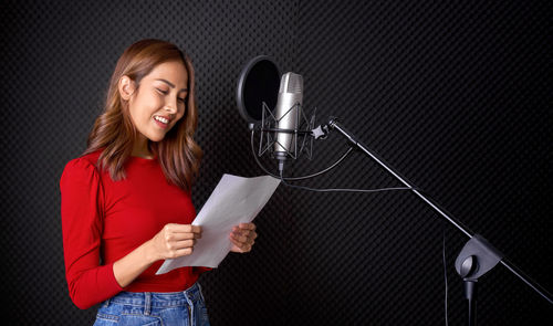 Full length of a smiling young woman using phone