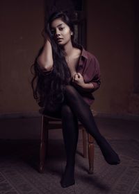 Full length of sensuous woman sitting on chair in room