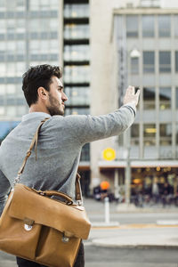 Rear view of businessman hailing taxi on city street