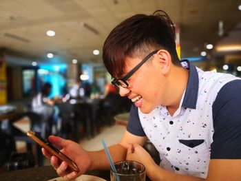 Smiling man using mobile phone while sitting at restaurant