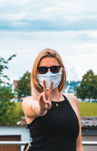 Portrait of beautiful young woman standing against sky