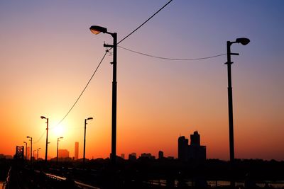 Silhouette street lights against sky during sunset