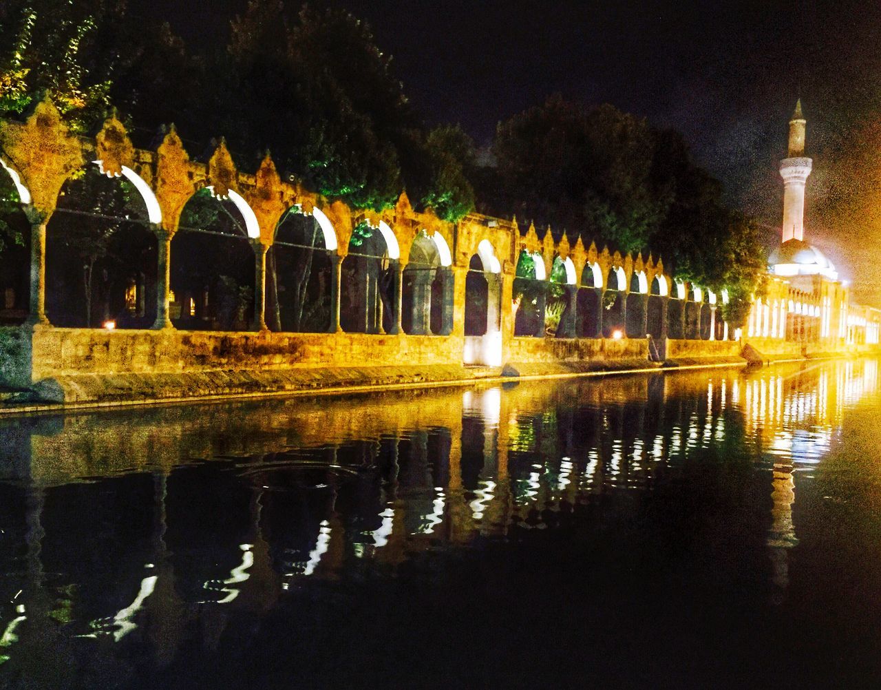 reflection, water, architecture, built structure, religion, place of worship, spirituality, night, illuminated, building exterior, waterfront, lake, pond, architectural column, outdoors, fountain, in a row, tree, famous place