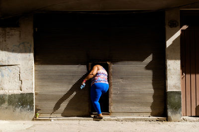 Portrait of woman standing against closed shutter