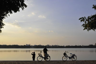 Men riding bicycle on water against sky