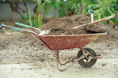 Closeup steel cart carrying the soil with shovels with blurred pile of soil background