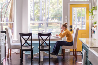 Side view of woman using laptop on table at home