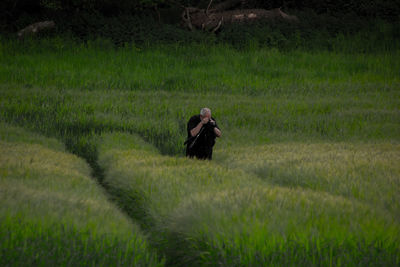 Man photographing while standing amidst plants in farm