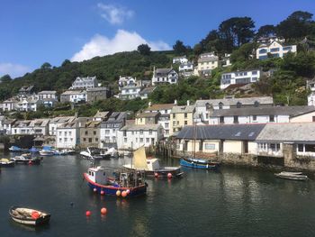 Boats moored in river by town against sky