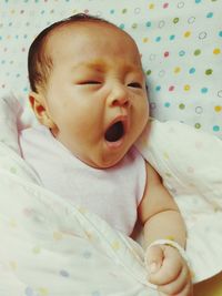 Cute baby girl yawning on bed