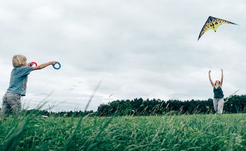 Low angle view of siblings playing on field against sky