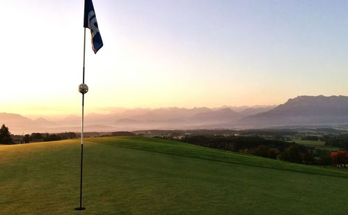 Flag on golf course at sunset