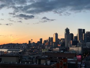 Modern buildings in city against sky during sunset