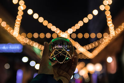 Close-up of hand holding illuminated lighting equipment at night