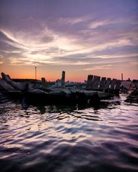 Scenic view of sea by buildings against sky during sunset