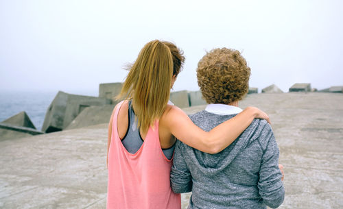 Woman with mother standing on pier against sky