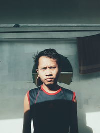 Portrait of young man standing against wall