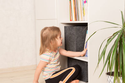 Little girl chooses a book in a bookcase at home. children's creativity and education