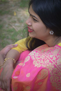 Young woman looking away while sitting outdoors