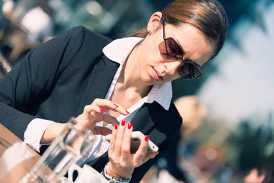 Businesswoman using smart phone at sidewalk cafe