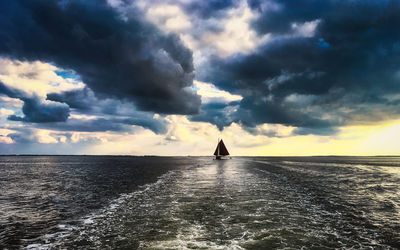 Silhouette man in sea against sky during sunset