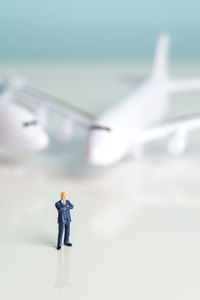 Close-up of airplane models and pilot figurine on table against blue background