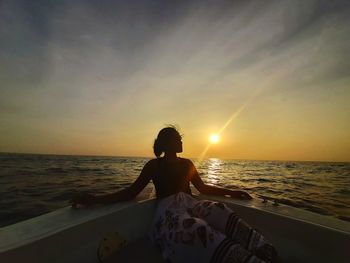 Woman on beach against sky during sunset