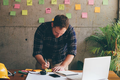 Architect writing on adhesive note in office