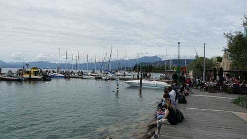 Boats moored at harbor against sky in city