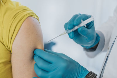 Doctor giving covid-19 vaccine on patient hand at examination room