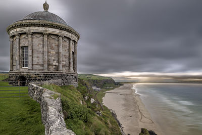 View of castle on beach against cloudy sky