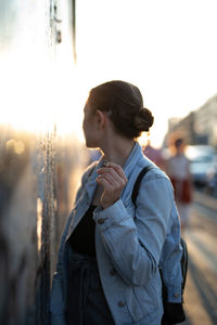 Woman holding cigarette while standing by wall in city