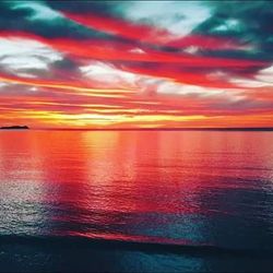 Scenic view of sea against dramatic sky during sunset