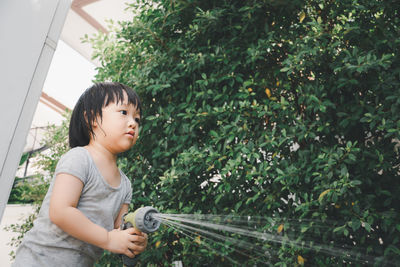 Cute girl watering plant outdoors