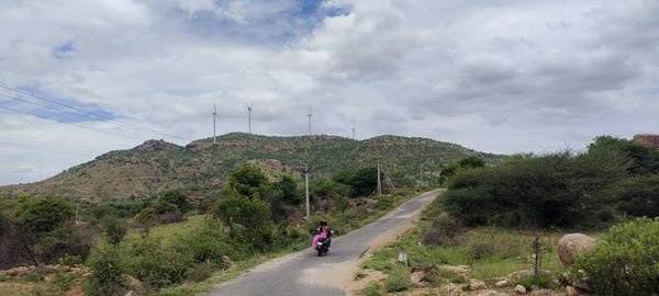 People riding motorcycle on road against sky