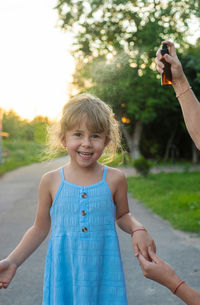 Portrait of young woman with arms raised standing on field