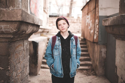 Portrait of young man standing against steps in alley