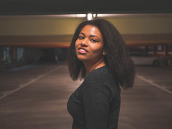 Portrait of smiling young woman standing by car