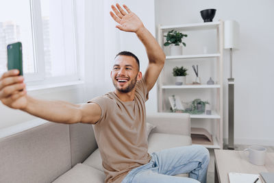 Portrait of young woman using mobile phone while sitting at home