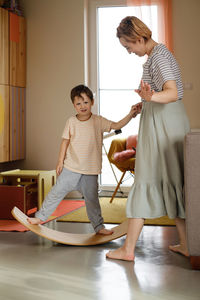 Child playing on balance board for toddlers in kids room. curvy rocker board used for motor physical