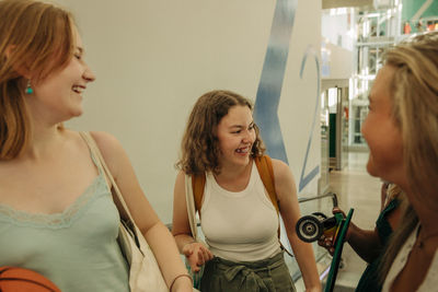 Happy teenage girl enjoying with female friends in mall