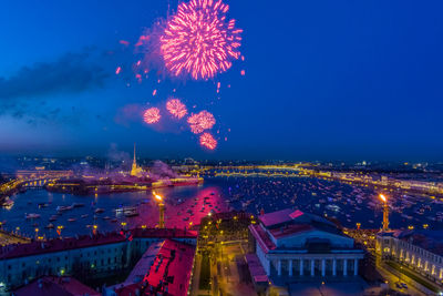 Firework display over river against buildings in city at night