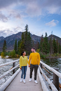 Rear view of people on footbridge against sky