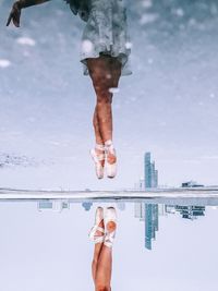 Low section of ballet dancer dancing while reflecting on puddle