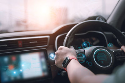 Cropped hand of man using smart phone in car