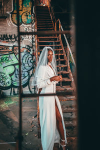 Woman with umbrella standing on graffiti wall