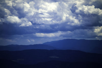 Scenic view of silhouette mountains against cloudy sky